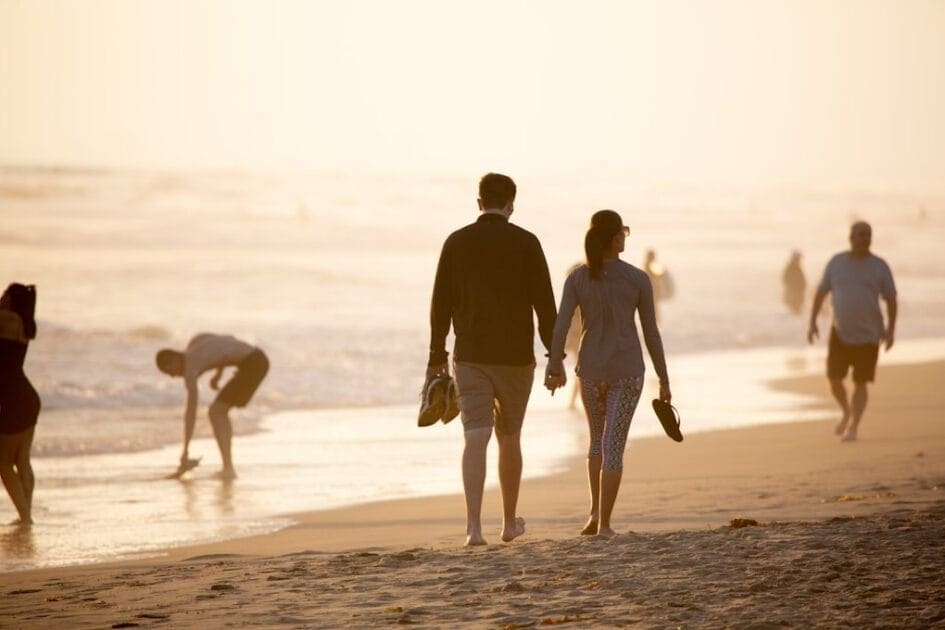 Man and woman holding hands while walking on beach after seeing their Naturopath Caloundra, Shella Hall.