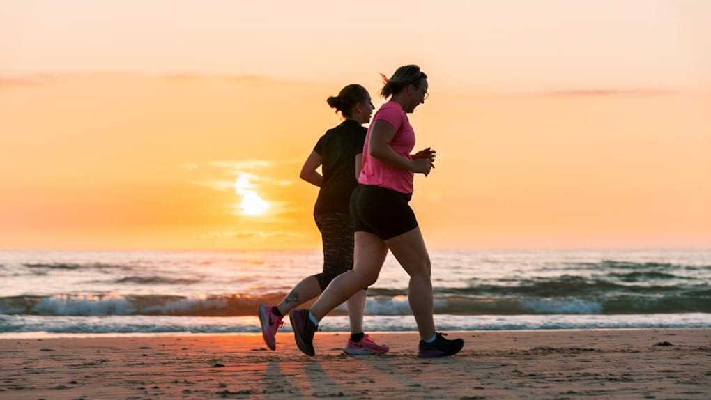 Two women running on beach at sunset. Hypnotherapy to Cease Smoking and Vaping. DNA Testing Brisbane. What does an Osteopath do. Brisbane Livewell Clinic