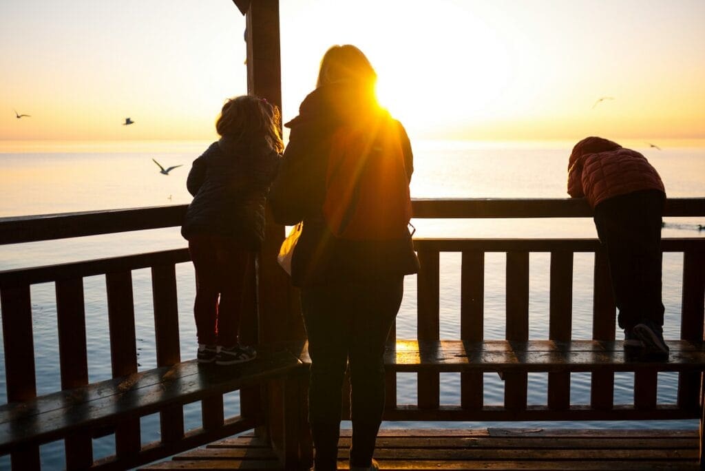 Family standing near a fence at sunset. Brisbane Wellness Centre.