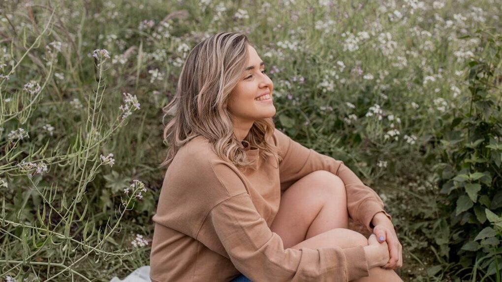 Woman in brown shirt sitting in a field of flowers