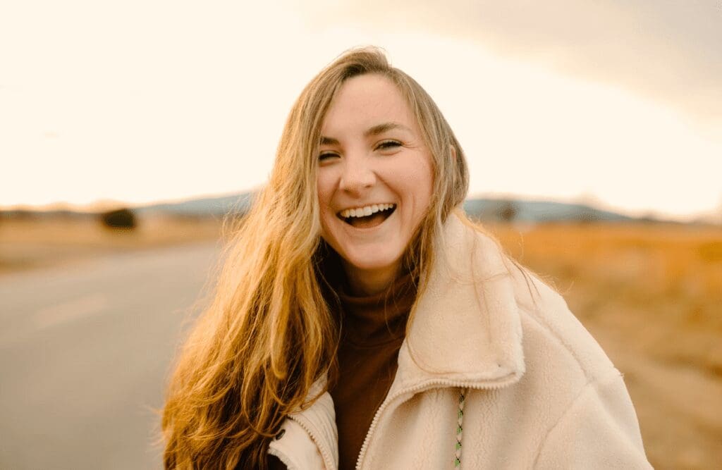 A cheerful young woman smiling brightly outdoors. Naturopaths. Heavy Metal Detox Naturopath. Brisbane Livewell Clinic