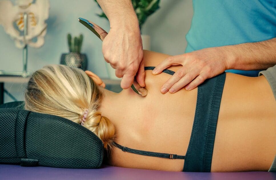 Masseur using scrapper tool to massage woman's back. Myofascial Release Therapy Massage Near Me. Brisbane Livewell Clinic