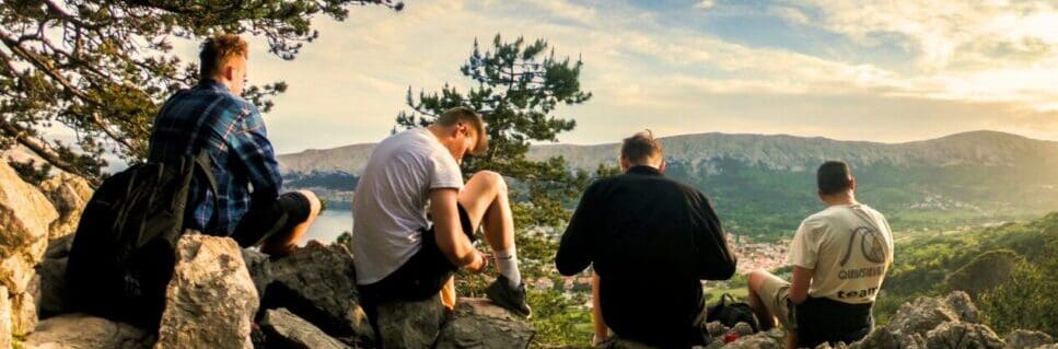 Four men seated on rocks facing mountain. Men's Health Supplements. Brisbane Livewell Clinic
