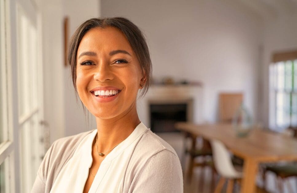 Smiling woman standing in front of a window. Full Genetic Testing Australia. Holistic Counsellor Brisbane. Osteopath for Neck Pain. DNA Testing Brisbane. Brisbane Livewell Clinic