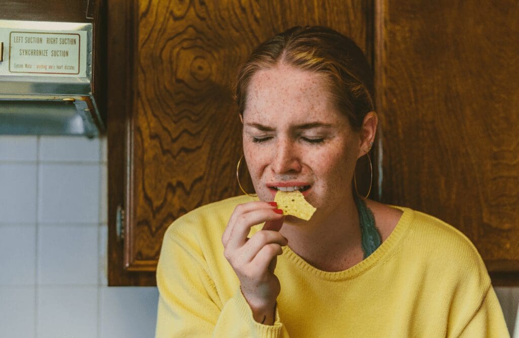 Woman eating chips in the kitchen. Binge eating. Brisbane Livewell Clinic