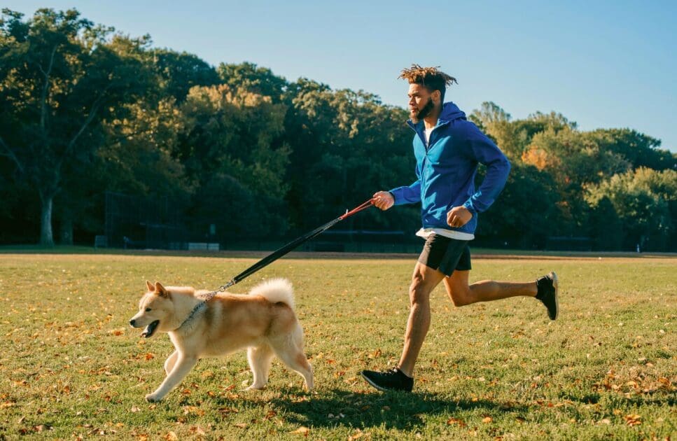 Man runs alongside his dog in a park. Dry Needling Near Me. Naturopath for Men's Health. Osteopath Morningside. Brisbane Livewell Clinic