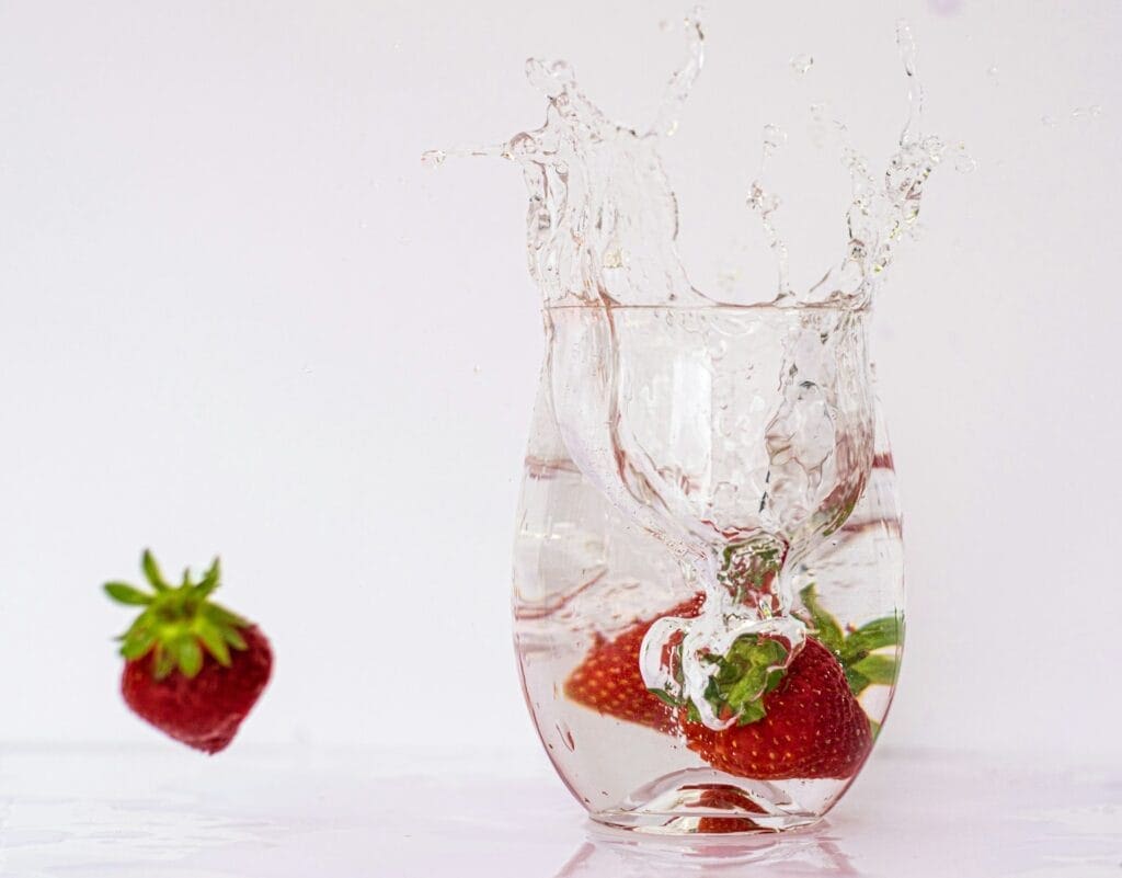 A strawberry splashing into a glass of water. Heavy Metal and Parasite Detox. Brisbane Livewell Clinic