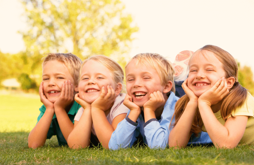 Three smiling children lying on the grass. ADHD Naturopath. Children's Naturopath. Heavy Metal Toxicity in Toddlers. Brisbane Livewell Clinic. Naturopathic Care for Children. Naturopath Brisbane at Brisbane Livewell Clinic