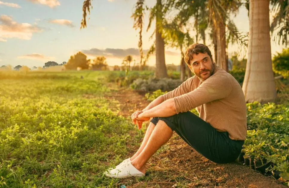 Man sitting in a field surrounded by tall palm trees under a clear blue sky. Hypnotherapy near Virginia. How hypnosis helps with anxiety. Hypnotherapy weight loss near me. Brisbane Livewell Clinic