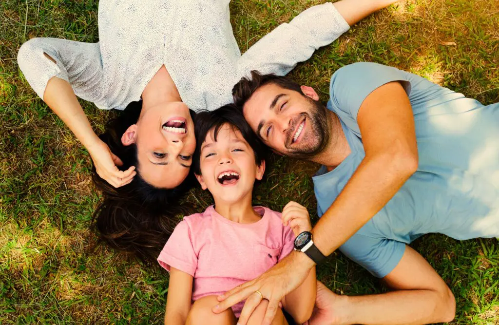 Family enjoying sunny day while lying together on the grass. Aftermath of Bowen Therapy. Family Counselling. Brisbane Livewell Clinic