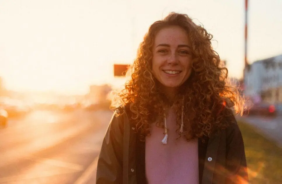 Woman standing and smiling in front of a bustling street. Hypnotherapy near Stafford. Hypnotherapy Services Brisbane. Naturopathic Remedies for Insomnia. Brisbane Livewell Clinic