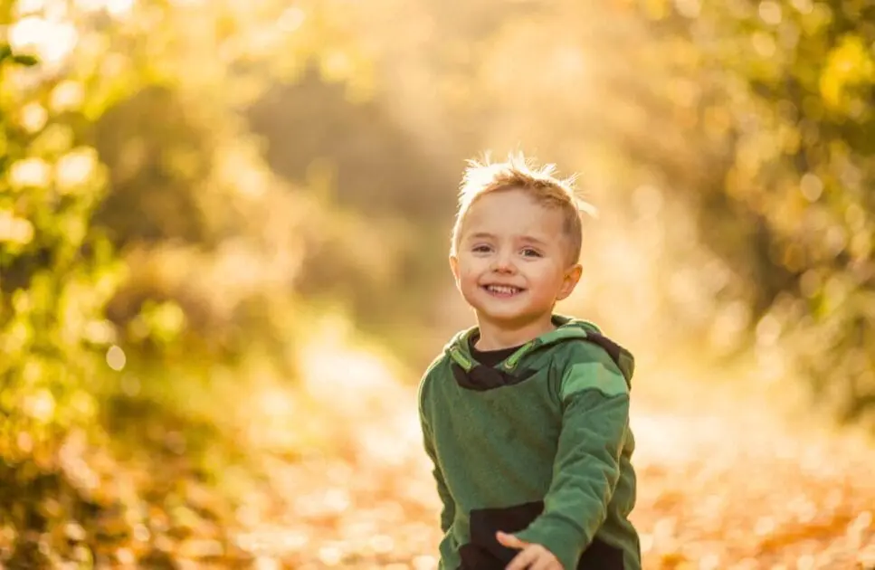 Smiling young boy walking through a forest during sunny day. Heavy Metal Detox for Kids. Naturopath for Children. Brisbane Livewell Clinic