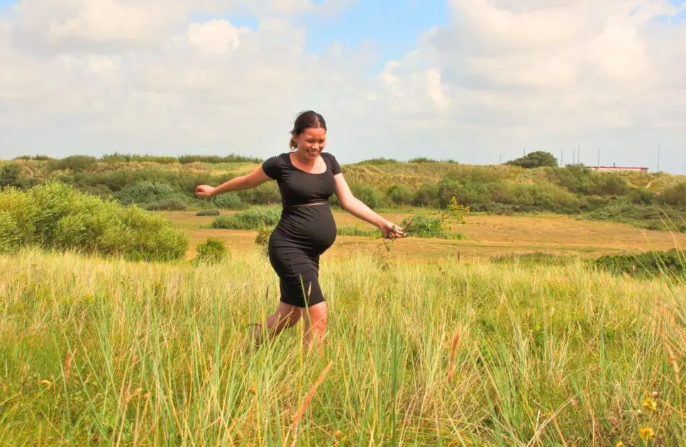 Happy pregnant woman walking in the field. Pregnancy Massage Near Me. Brisbane Livewell Clinic