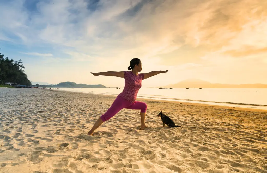 A woman practices yoga on a sandy beach at sunrise. Naturopath North Brisbane. Hip Flexor and Tight Hips Osteopath. Brisbane Livewell Clinic