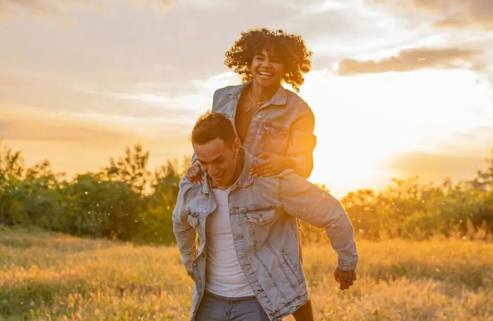 Man carries a woman in a field during a beautiful sunset. Hypnotherapy near Stafford. Relationship Counseling Near Me. Brisbane Livewell Clinic