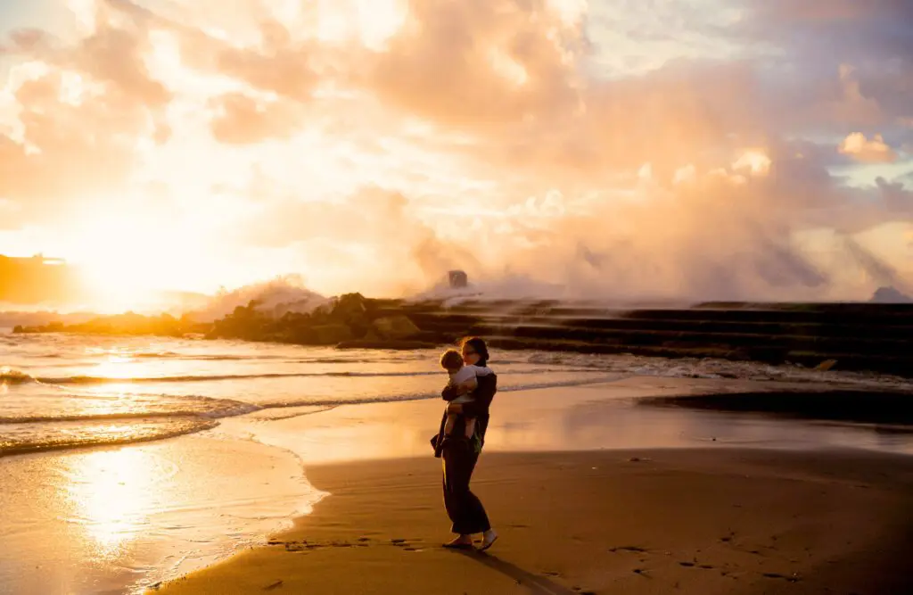 Woman standing on the seashore carrying her child. Nutritionist Wavell Heights. Brisbane Livewell Clinic