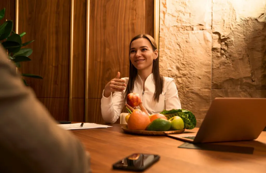 Nutritionist holding an apple while talking to her patient. Nutritionist Wavell Heights. Nutrition Brisbane. Brisbane Livewell Clinic