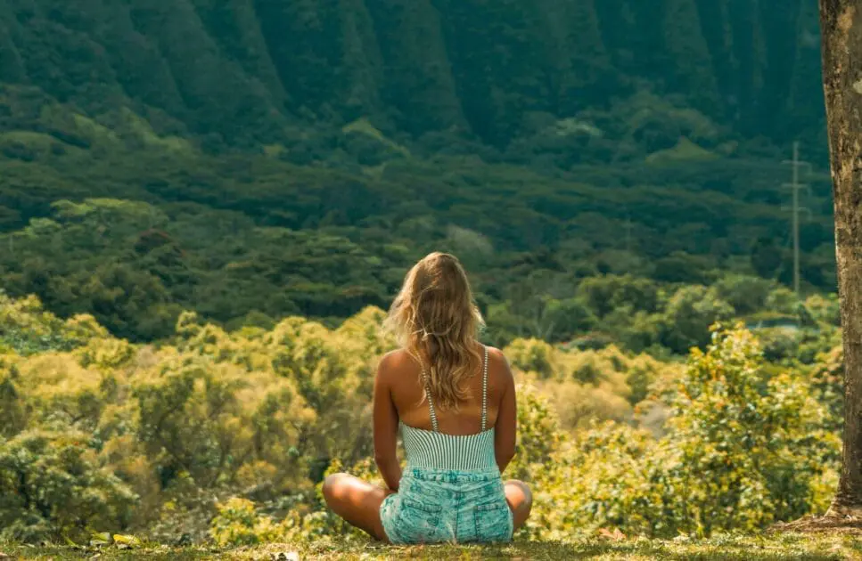 Woman sitting on the grass, looking at the mountain in fron of her. Hypnotherapy near Gordon Park. Osteopath Help with Posture. Brisbane Livewell Clinic